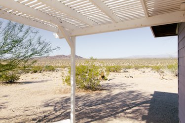a view of desert scrub and hills in the distance seen from a covered porch