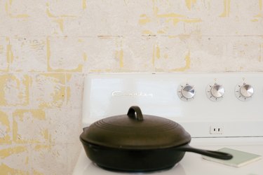 a cast iron pan with a lid on the burner of a vintage crossly stove