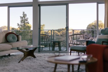 a view of the desert through large windows and a room full of mid-century furniture