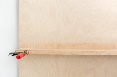 a front view of a recently glued shelf held in place with a clamp