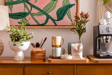 Wood cabinet with flowers and coffee station against pale pink wall