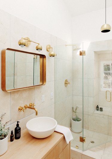 a light, airy bathroom with off-white tile, a blonde wood vanity, and a white raised basin sink