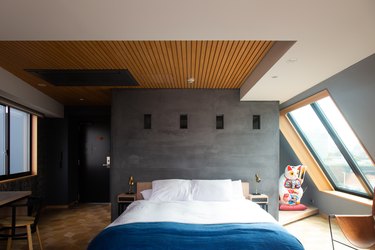 a hotel room with a wooden ceiling, dark gray sloping walls, and a large lucky cat figurine