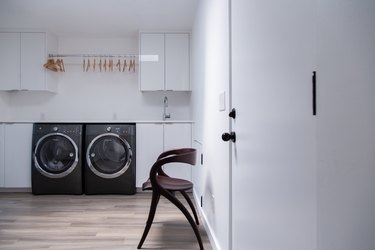 Minimalist laundry room with modern chair and black washer and dryer