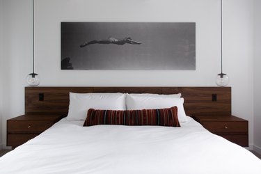 Double wood nightstands and globe lights on either side of a bed, with a wood headboard.