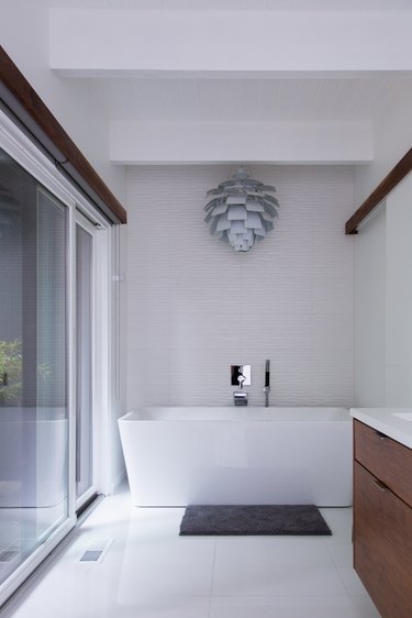 Minimalist bathroom with a freestanding tub and modern chandelier.