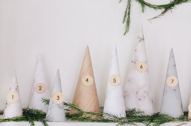 White, gray, beige paper cones with numbers on mantel with pine