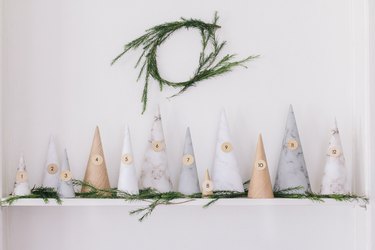 Gray and beige paper trees advent calendar with pine on mantel