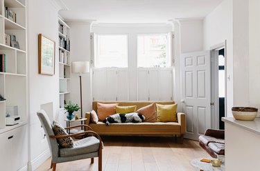 Modern living room with leather couch, chair, dog, bookshelves, and windows shining natural lighting