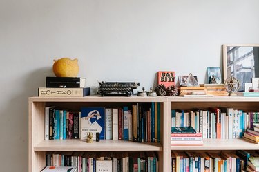 Top of bookshelf with books and knick-knacks against white wall