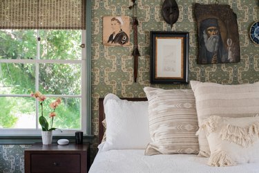 white linen bed with wallpaper and vintage photos behind it