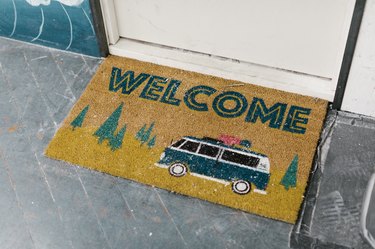 A door mat that says, 'welcome' and has an image of a camper van and trees.