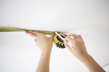 using a measuring tape to help mark locations on the ceiling