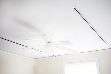 a ceiling fan between two curtain rods suspended from the ceiling with stick-on hooks