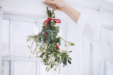 a diy bunch of mistletoe with a red ribbon is hung in a doorway