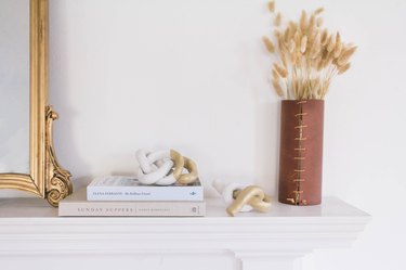 Mantel with clay knot sculptures and leather vase with dried plants