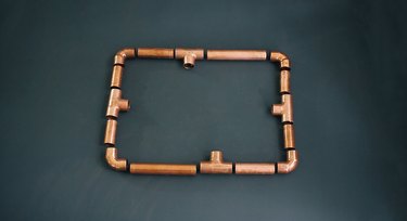 pieces of copper pipe laid out on a table in nearly their final position