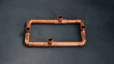 a rectangular copper candelabra base made from copper pipe