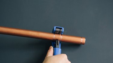 using a pipe cutter to trim copper pipe