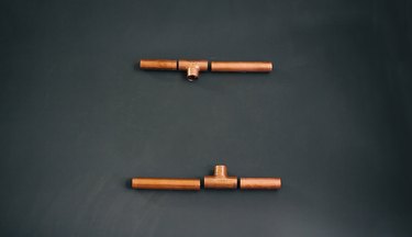 pieces of copper pipe that will become opposite sides of a candelabra base laid out on a table