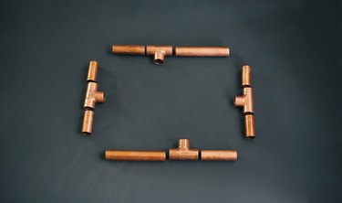 pieces of copper pipe that will become the four sides of a candelabra base laid out on a table