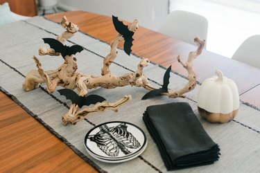 a centerpiece made from a found branch and paper bat cut-outs in the middle of a table