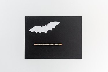 a paper bat template, black construction paper, and a pencil