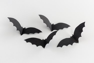 black paper bat cut-outs creased in the middle to look like they're flying