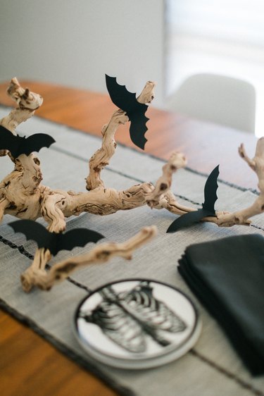 a centerpiece made from a found branch and paper bat cut-outs in the middle of a table