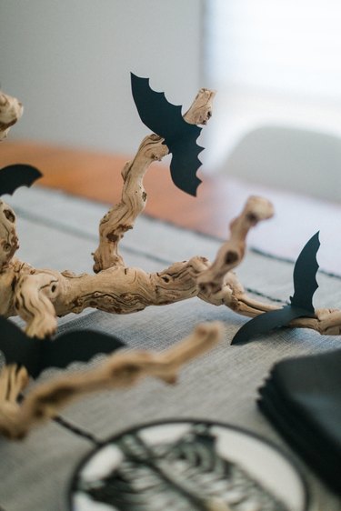 a centerpiece made from a found branch and paper bat cut-outs in the middle of a table