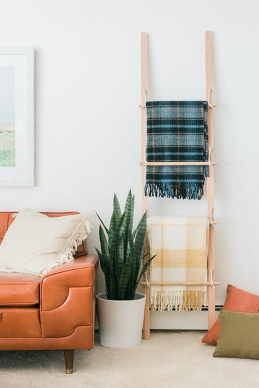 Wood blanket ladder with plaid blankets with potted plant and leather sofa