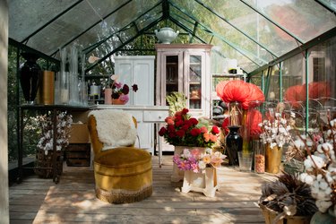 Greenhouse with mismatched, shabby chic furniture, plants and vases