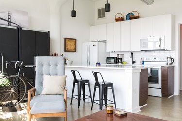 white, modern kitchen with black barstools and black cabinets