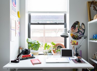 Desk with white desk lamp pushed up against open window