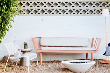 a pink bench with mid-century lines on gravel in front of a cone-shaped fire pit