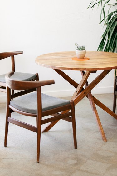 a midcentury outdoor dining set with sturdy dark brown chairs and a round table with criss-crossing legs