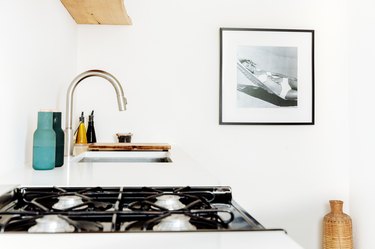 a stark white kitchen features a framed photo of a woman in a bikini lounging in a hammock