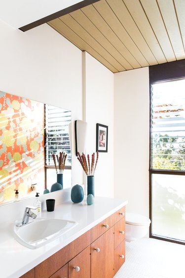 Midcentury bathroom with beamed ceiling and wood cabinets