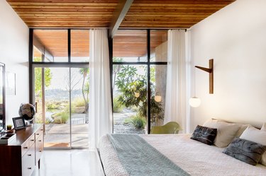 A bedroom with floor-to-ceiling windows with twin sheer window treatments