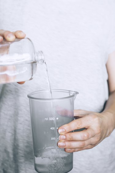 pouring white vinegar into a measuring cup