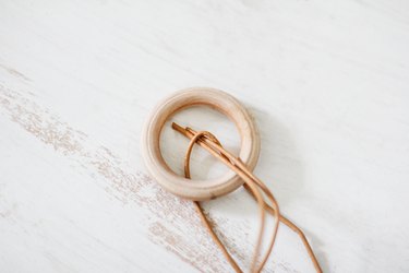a leather thong is knotted through a circular wooden hanger