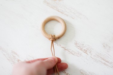 a leather thong is looped through a circular wooden hanger