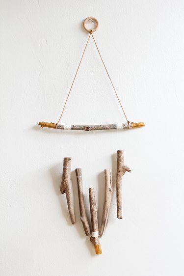 a wall hanging made of several vertical pieces of driftwood suspended from a horizontal one