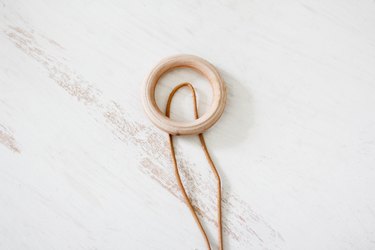a leather thong is looped through a circular wooden hanger
