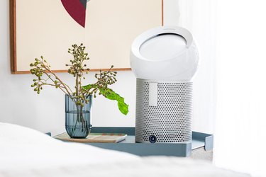 Air purifier on nightstand with blue glass vase with flowers