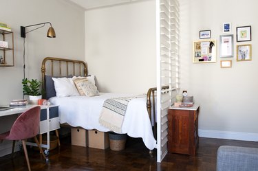 A bedroom with a white shutter room diver and an office desk