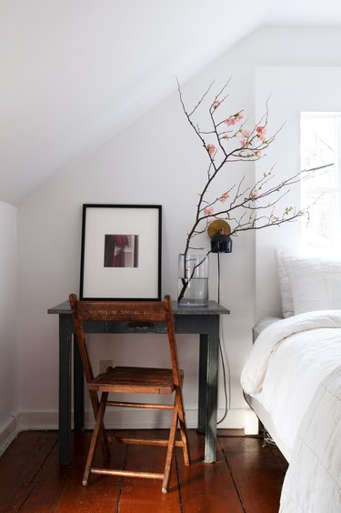 Bedroom with white walls and small desk with wood furniture and floors