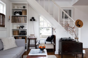 Staircase idea in living room with white walls, built in bookshelves, and dark wood farmhouse furnishings