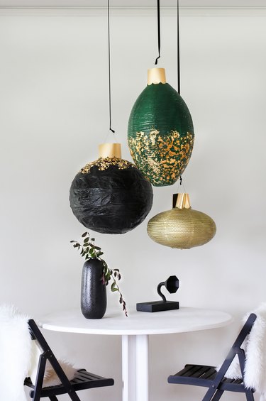 Green, gold and black lanterns with white table with black chairs and black decor