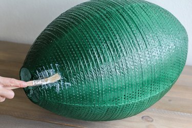 Paint brush applying adhesive on large green lantern